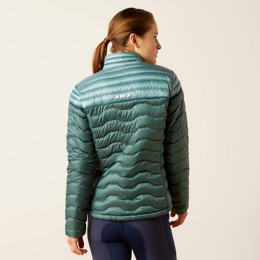 Back view of a young woman wearing a light green two-tone ariat puffer jacket with pockets, standing against a neutral background